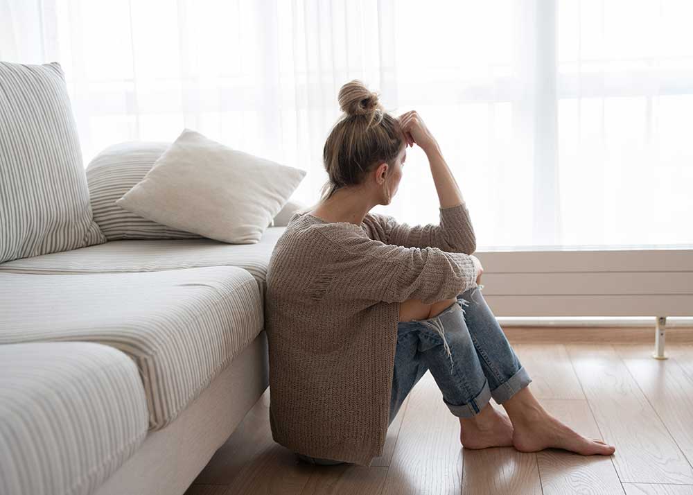 Depressiv verstimmte Frau sitzt auf dem Boden